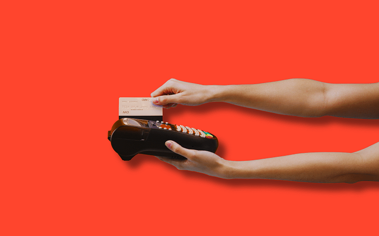 Hands inserting a credit card into a payment terminal, offering a payment fraud guide for businesses. This image highlights secure transaction tips against fraud, set against a vibrant red background for attention.