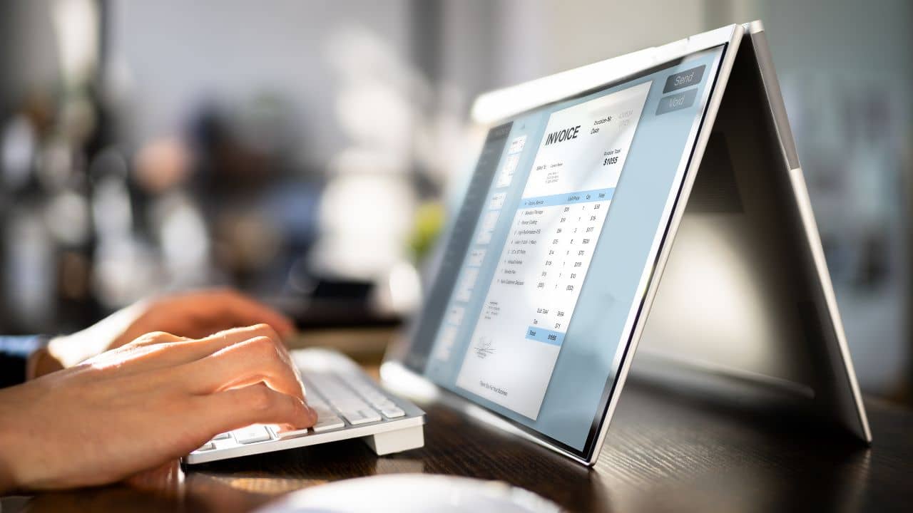 Close-up of someone working on a computer, with a digital invoice displayed prominently on the screen. The image suggests invoicing tasks and financial management software Billpay.