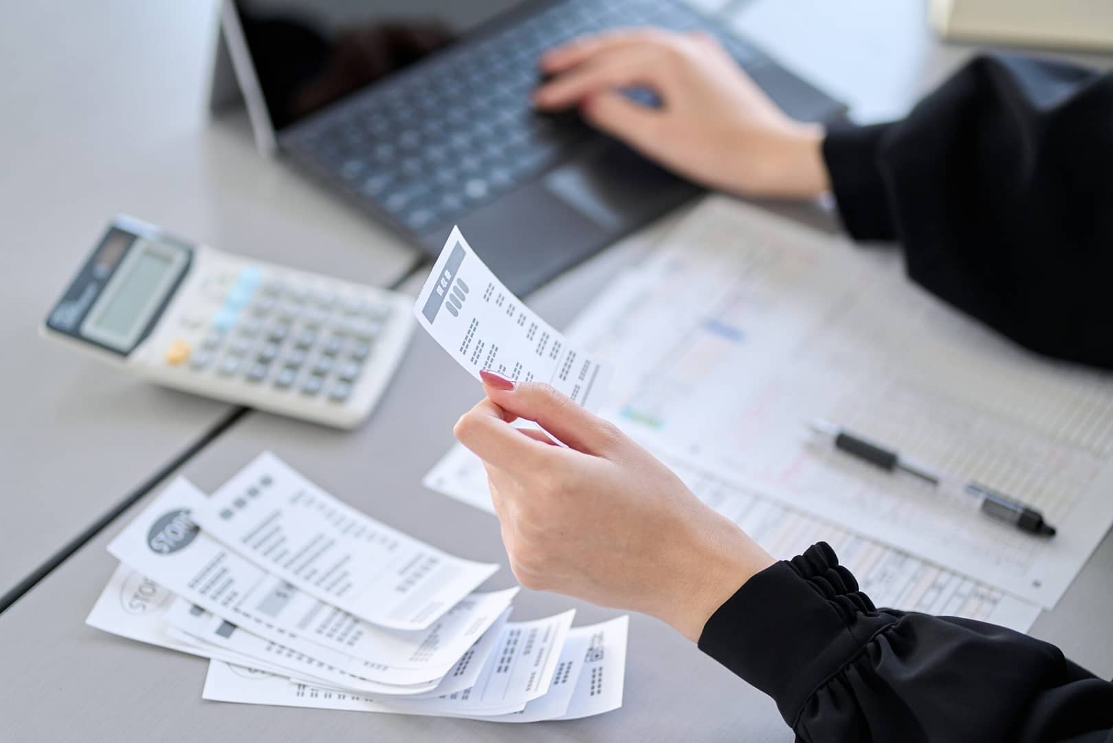 A person reviewing multiple invoices. Some financial documents are also present, indicating an invoice processing or financial management task.